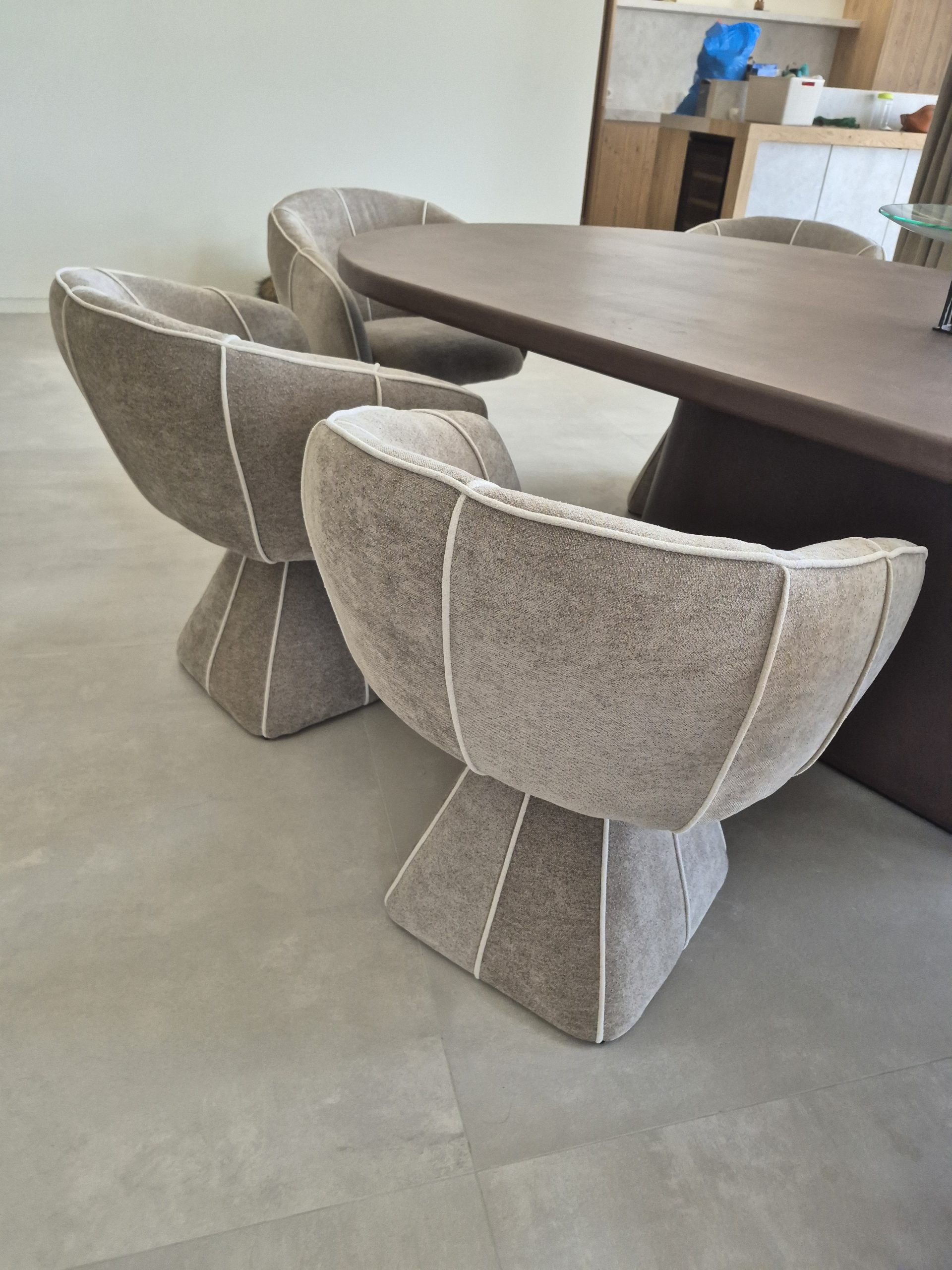 Butacas tapizadas de respaldo envolvente y ribete claro junto a mesa de comedor — Casa Bancal