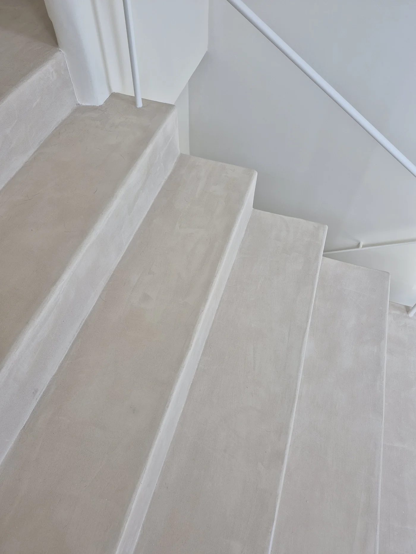 Detalle de escalera revestida en microcemento continuo color arena — Casa Bancal