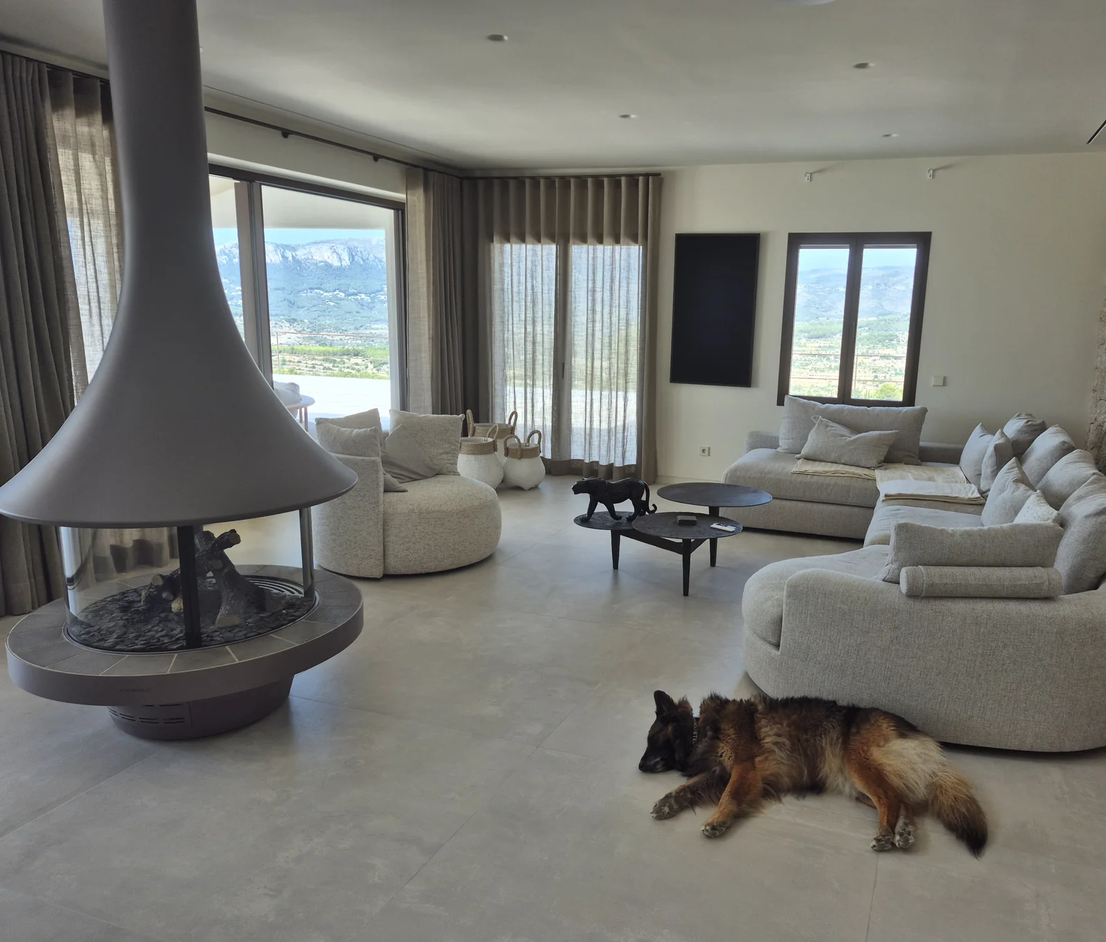 Salón con muro de piedra seca y chimenea suspendida — Casa Bancal, Costa Blanca