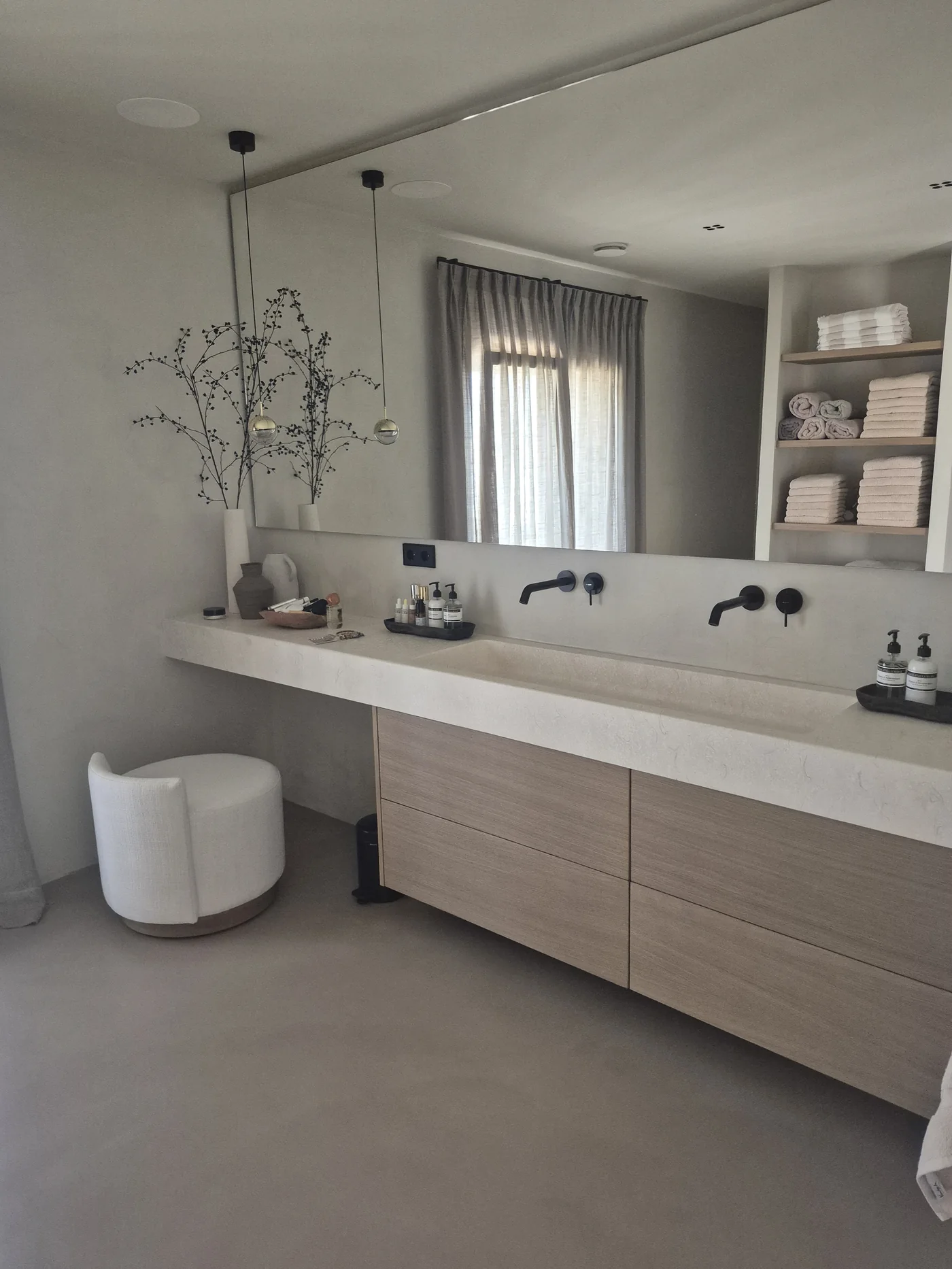 Baño principal con encimera monolítica de microcemento, doble grifería negra y mueble de roble — La Cumbre