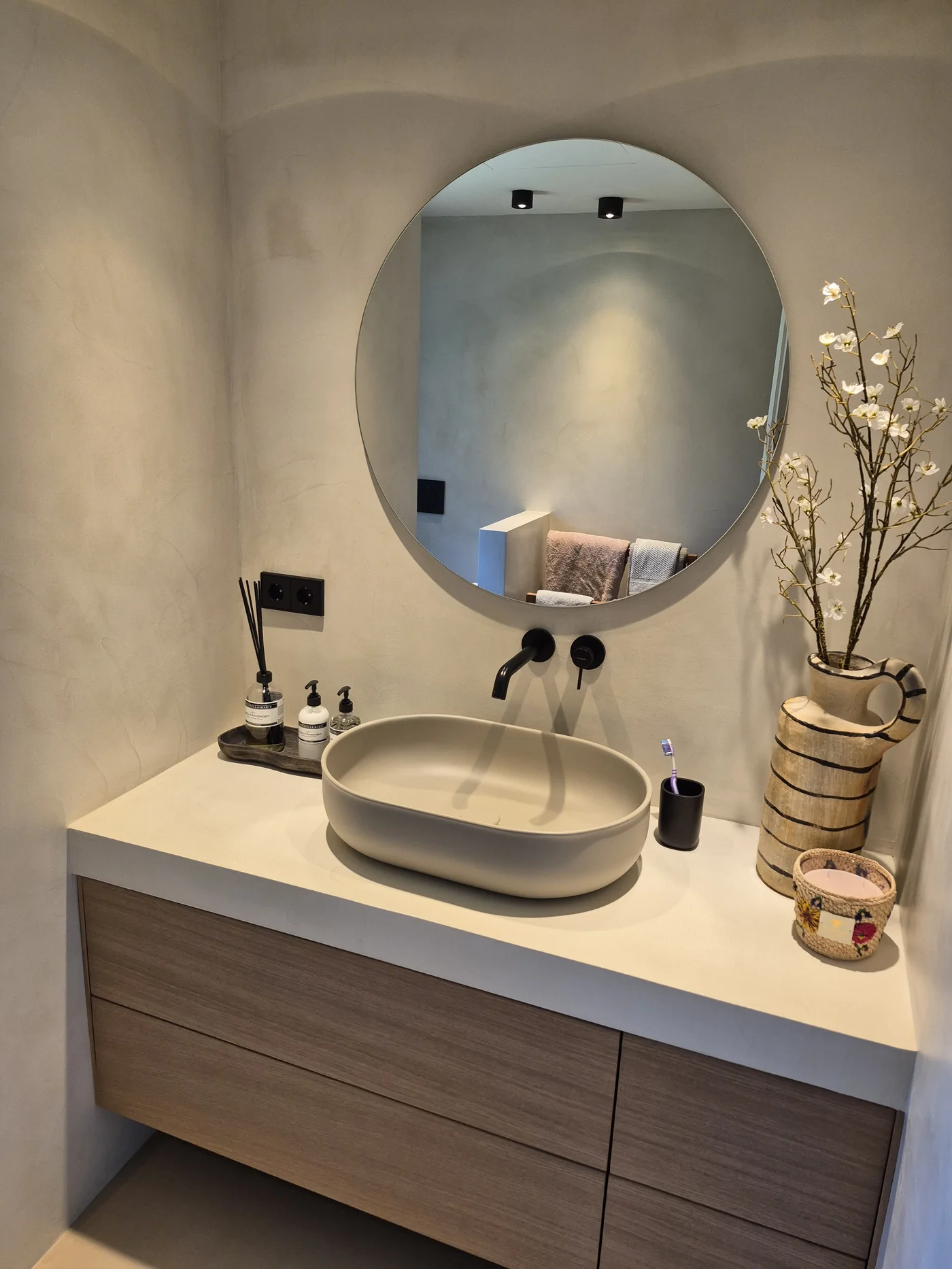 Aseo revestido en microcemento con espejo circular y lavabo ovalado sobre encimera — La Cumbre