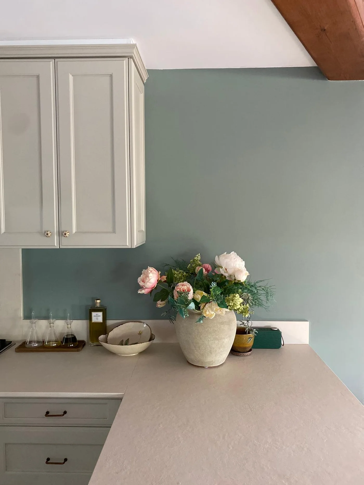 Cocina con pared en verde salvia y carpintería pintada a juego, bajo viga de madera — Jávea